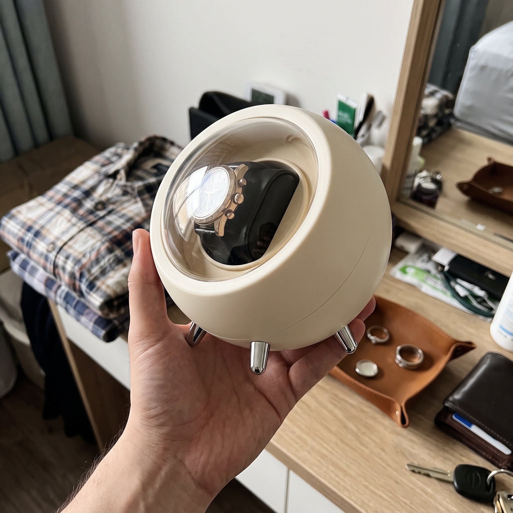 Hand supporting an Cream winder above a dresser